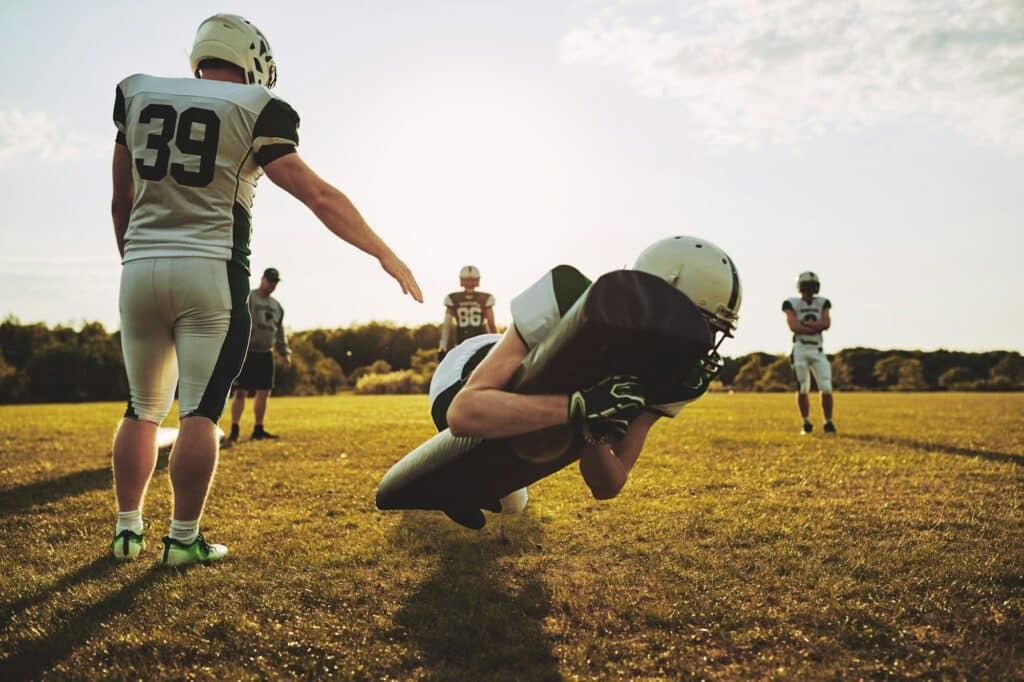 American football players practicing tackles on a football field